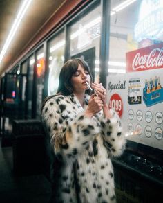 a woman standing in front of a vending machine holding a cell phone to her ear