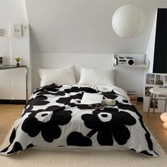 a bed with black and white flowers on it in a room next to a wall