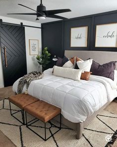 a bedroom with black walls, white bedding and brown foot stools in front of the bed