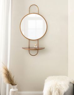 a round mirror mounted on the wall above a shelf in a living room with fur