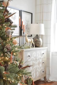 a decorated christmas tree with pine cones and ornaments on it in front of a mirror