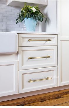 a white kitchen with gold handles and drawers