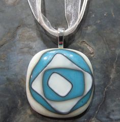 "I love working with the french vanilla and turquoise glass.  These are two of my favorite glasses to work with.  This pendant looks fantastic.  Normally I go with a more symmetrical, structured pattern or a zig zag pattern when using these colors.  With this pendant, I randomly place pieces of the french vanilla and turquoise glass and let the magic of the kiln take over.  This pendant measures approximately 1.375\" w by 1.375\" l (3.4 cm x 3.4 cm).  It features layers of French Vanilla and Tur Modern Turquoise Glass Jewelry, Fused Glass Dishes, Glass Christmas Decorations, Fused Glass Pendant, Ribbon Necklace, Fused Glass Jewelry, Glass Fusing, Turquoise Glass, French Vanilla