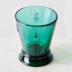 a green glass cup with a bug on it