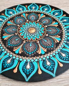 a black and blue plate with an intricate design on it's side, sitting on a wooden surface