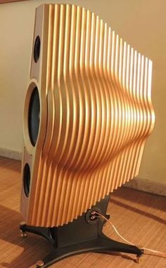 a large speaker sitting on top of a wooden floor next to a wall with speakers in it