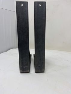 pair of black metal bookends on white tableclothed floor with wall in background