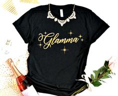 Why be a Grandma when you can be a Glamma! We all know a Glamma and She will love this shirt! She can pair this sparkly shirt with her favorite jewelry and feel like a Queen. Not all Tshirts are alike, this High End Quality Vneck t shirt will be her new favorite shirt. Black shirt with Glamma in Gold Sparkly Lettering. * This is a VNeck Ladies Cut Shirt and is True to size. If you like extra room, go up a size. * Want a different color shirt, just message me. I would be happy to do that for you. Gold Tops With Letter Print For Gifts, Gold Short Sleeve Top As Gift, Gold Crew Neck Top As Gift, Gift Ideas For Grandma, Sparkly Shirt, Grandmother Birthday, Ladies Cut, Mermaid Halloween, Mermaid Shirt