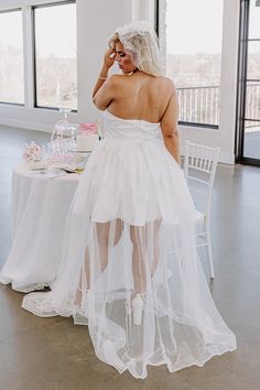 - This gorgeous dress is giving fairytale vibes! - Material with a satin finish overlaid by tulle - A built-in partial lining ending upper thigh length - Floral accents - A straight strapless neckline with a interior non-slip strip - Built in padding - Back zip closure - A flowy silhouette that ends in a straight maxi length hemline Sheer Tulle Corset Dress For Wedding, Sheer Strapless Wedding Dress, Strapless Sheer Wedding Dress, White Satin Dress With Detachable Train, White Tulle Corset Dress For Wedding, Strapless White Organza Dress, White Tulle Corset Wedding Dress, Strapless Sheer Tulle Corset Dress, Strapless Dress With Fitted Bodice For Bride