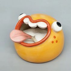 a yellow toy with a mouth and tongue sticking out from it's inner circle