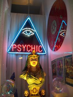 a neon sign that says psychic and an egyptian statue in front of it with the eye of providence