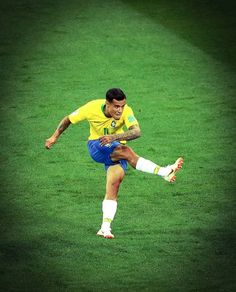 a man kicking a soccer ball on top of a lush green field with yellow and blue colors