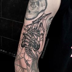 a man's arm with a spider web tattoo on it and a skull in the background