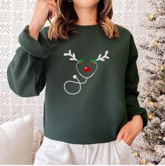 Get into the festive spirit with our "Nurse Sweatshirt." This Christmas-themed sweater features playful reindeer antlers on a stethoscope, making it a delightful choice for RNs, ER professionals, and nursing school students. Embrace the holiday season in comfort and style, and let this cozy crewneck sweatshirt become a fun and heartwarming addition to your wardrobe. Whether you're working through the holiday season or celebrating with your healthcare family, this sweatshirt is perfect for spread Reindeer Antlers, Anatomical Heart, Cardiology, Heart Gifts, Funny Sweatshirts