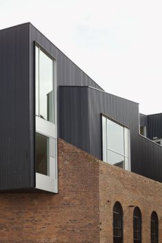 a brick building with two windows on the front and side of it's facade