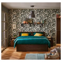 a bedroom with green bedding and wallpaper in the background, along with wooden flooring