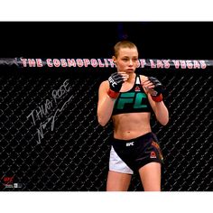 a woman standing in front of a fence with her hands on her hips and wearing boxing gloves