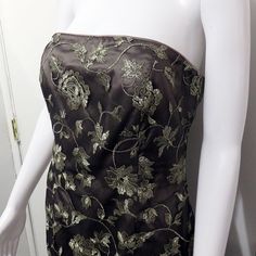 a mannequin wearing a black and gold dress with flowers on it's side