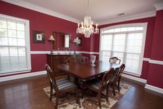 a dinning room with red walls and wooden flooring is pictured in this image