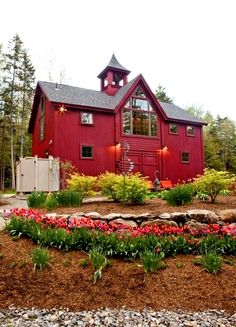 a red barn with tulips in the foreground