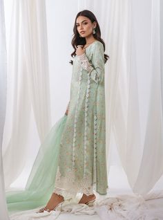 opt for elegant garden of ethereal beauty with our pastel green floral printed outfit, a masterpiece that embodies the essence of springtime elegance. The long shirt boasts with intricate cut work adorning the sleeves and hemline, The neckline is adorned with exquisite embroidery, reminiscent of blooming blossoms. Completing the ensemble with a matching organza dupatta, and pants the subtle detailing adds a touch of refinement. Shirt: Printed ShamosePants: Raw SilkDupatta: Organza Elegant Lawn Suit With Intricate Embroidery For Spring, Spring Wedding Lawn Suit With Lace Work, Pista Green Lawn Suit For Summer Wedding, Pista Green Floral Print Sets For Spring, Summer Wedding Lawn Suit In Pista Green, Elegant Pista Green Dress For Spring, Elegant Pista Green Spring Dress, Summer Wedding Pista Green Lawn Suit, Summer Lawn Suit In Pista Green With Dupatta