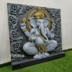 an elephant statue sitting on top of a green grass covered floor next to a wall