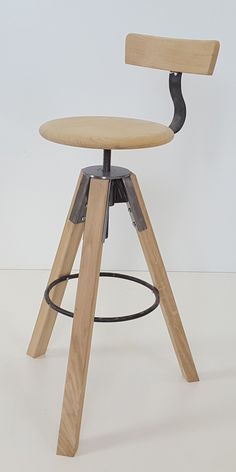 a wooden and metal stool with an adjustable seat on the backrest, in front of a white wall