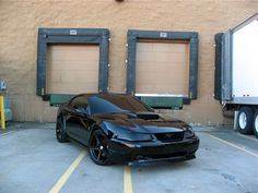 a black sports car parked in front of two garage doors