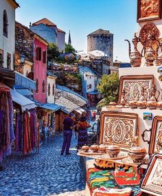 a cobblestone street lined with shops and people walking around it in the city