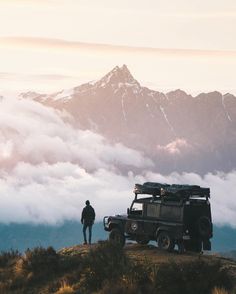 a man standing on top of a hill next to a truck