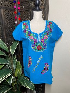 "Precious Embroidered Blouse made in Puebla, Mexico by our Mexican partners. Super light weight and fresh looking. The embroidered design is beautiful and delicate. All the work is clean, and with a professional finish and hand embroidered. You will look gorgeous for a friends night out or a summer cookout day, your call. You will Love it either way.... :) Blouse STYLE DETAIL Overview * soft cotton fabric * round-neck * hand embroidered design * short sleeves * 22\" UNDERARM TO UNDERARM, 28\" SH Cotton Embroidered Top With Resham And Short Sleeves, Traditional Blue Tops With Floral Embroidery, Traditional Cotton Blouse With Tonal Embroidery, Short Sleeve Cotton Top With Resham Embroidery, Cotton Short Sleeve Top With Resham Embroidery, Cotton Short Sleeve Blouse With Resham Embroidery, Blue Short Sleeve Tops For Festivals, Blue Floral Embroidered Blouse For Festivals, Traditional Short Sleeve Tops With Tonal Embroidery