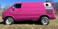 a pink van parked on top of a grass covered field