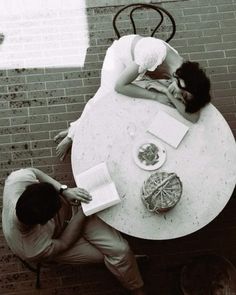 two people sitting at a table with books and papers