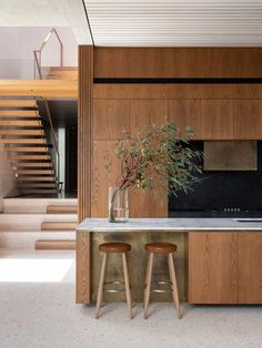 a kitchen with two stools next to a sink and counter top in front of stairs