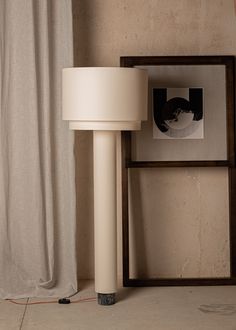 a lamp sitting on top of a white floor next to a framed photo and a wooden frame