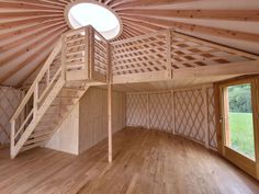 an empty room with wood floors and wooden stairs in the center, next to a round window