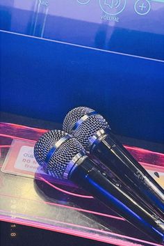 two microphones sitting on top of a clear plastic case next to a blue screen