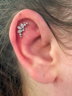 a close up of a person's ear with a small diamond flower on it