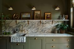 a kitchen with green cabinets and marble counter tops, gold faucets and brass pulls