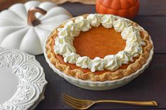 a pumpkin pie sitting on top of a table next to a white plate and silverware