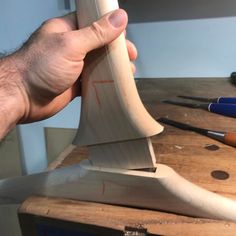 a person holding a knife on top of a wooden cutting board next to other tools