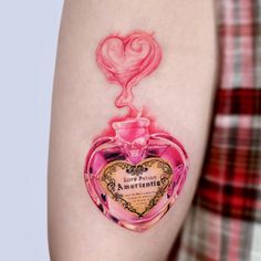 a woman's arm with a tattoo on it and a pink perfume bottle in the shape of a heart