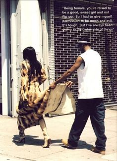 a man and woman walking down the street with a large animal print coat over their shoulders