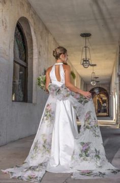 a woman in a wedding dress is standing on the sidewalk with her back to the camera