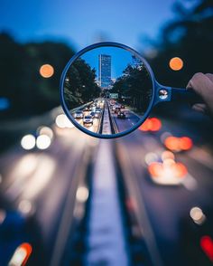 a person's hand holding a magnifying glass over a city street at night