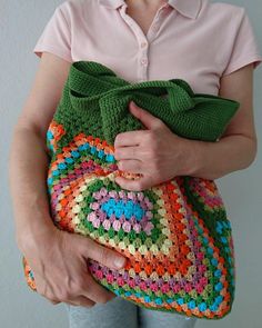 a woman holding a crocheted purse in her hands