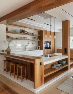 an open kitchen with wooden shelves and white counter tops, along with bar stools