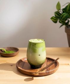 a green drink sitting on top of a wooden plate