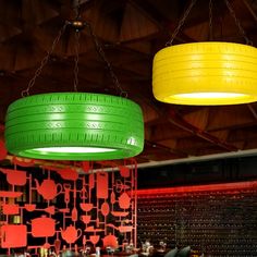 two green and yellow tires hanging from chains in a restaurant with red walls behind them