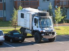 a white truck parked in a parking lot next to a building with balconies